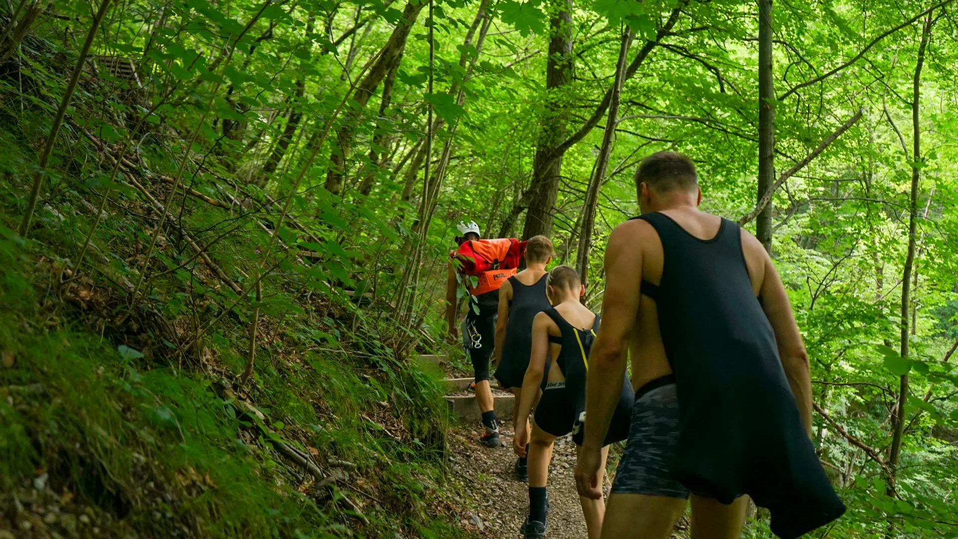 Canyoning group hiking through a green forest in the Soča Valley on the way to the canyon.