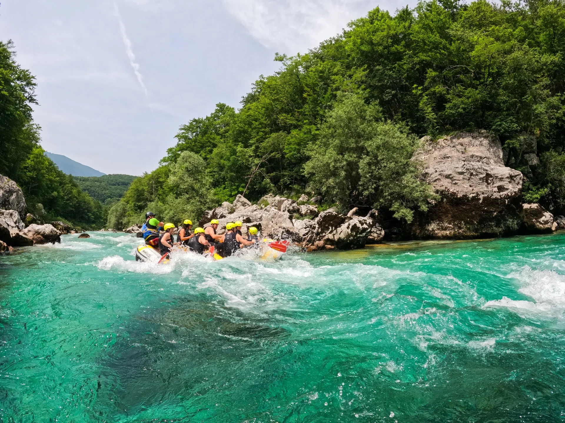 Classic rafting group paddling through whitewater rapids on the turquoise Soča River.