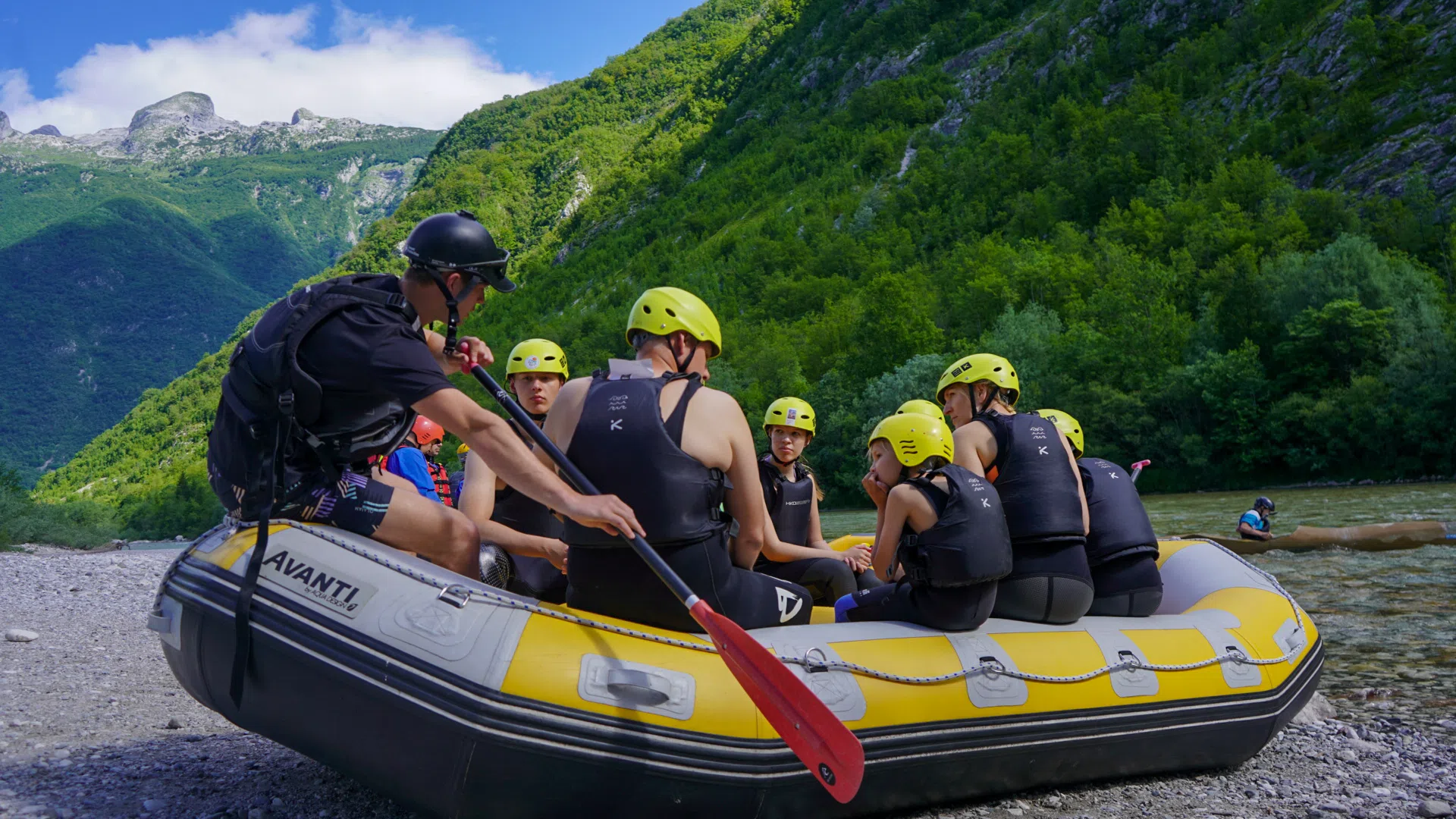 Relaxed rafting guide talking with guests beside the Soča River
