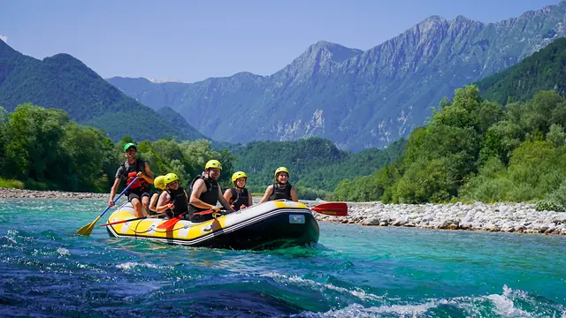 Relaxed rafting group enjoying the Soča River beneath the mountains